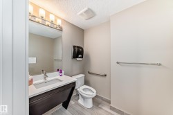 Bathroom featuring a vanity with a white countertop, a mirror with overhead lighting, and light-colored walls - 