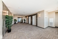 The property features a well-lit lobby with recessed lighting and wall sconces, showcasing a patterned floor, and two elevators with dark wood-toned surrounds - 