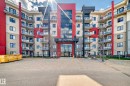 The property features a modern building exterior with a striking red, gray, and cream color palette - 506 11080 Ellerslie Road, Edmonton, AB  - Outdoor With Balcony With Facade 