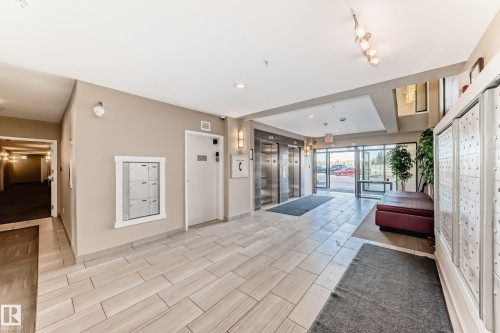 The property features a bright and spacious lobby with tiled flooring, two stainless steel elevators, and an array of mailboxes - 506 11080 Ellerslie Road, Edmonton, AB - Indoor Photo Showing Other Room