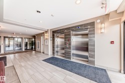 The property features a bright and spacious lobby with light-colored tile flooring, two stainless steel elevators, and contemporary wall sconces - 