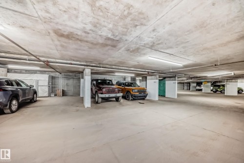 Underground parking garage featuring concrete floors and ceilings, along with ample overhead lighting - 506 11080 Ellerslie Road, Edmonton, AB - Indoor Photo Showing Garage