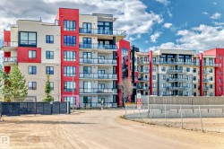 The property is an apartment complex featuring a modern exterior with red and beige facade panels, and glass balconies - 