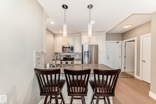 The kitchen features white cabinetry, stainless steel appliances, and a light-colored countertop - 506 11080 Ellerslie Road, Edmonton, AB - Indoor Photo Showing Kitchen With Stainless Steel Kitchen With Double Sink