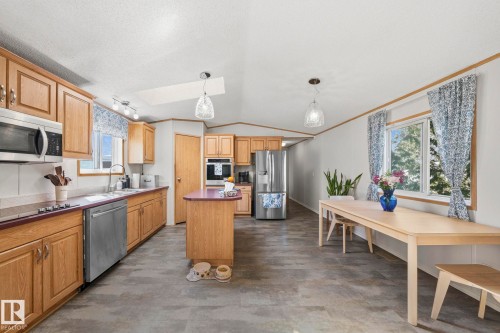 The kitchen features wood cabinetry, a central island with a countertop, stainless steel appliances, and a skylight - 66 Evergreen Park, Edmonton, AB - Indoor Photo Showing Kitchen