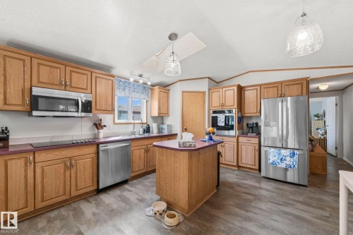 The kitchen features wood cabinetry, stainless steel appliances, and a central island - 66 Evergreen Park, Edmonton, AB - Indoor Photo Showing Kitchen