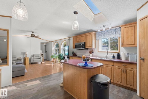 The kitchen features wood cabinetry, a stainless steel microwave, and a skylight providing natural light - 66 Evergreen Park, Edmonton, AB - Indoor Photo Showing Kitchen