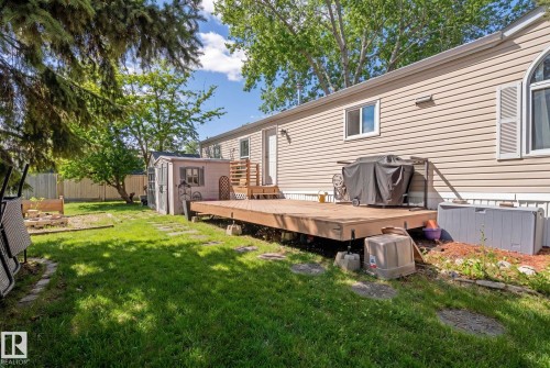 The property features a spacious backyard with a well-maintained lawn, a wooden deck, and a storage shed - 66 Evergreen Park, Edmonton, AB - Outdoor With Deck Patio Veranda