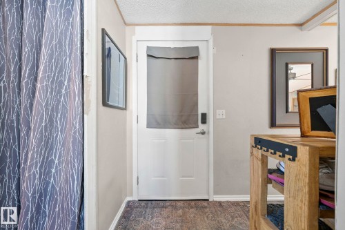 Entryway with a white door, a patterned floor covering, and a wooden storage unit - 66 Evergreen Park, Edmonton, AB - Indoor Photo Showing Other Room