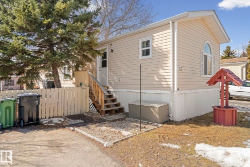 The property features beige siding, a white picket fence, and a wooden porch with stairs - 66 Evergreen Park, Edmonton, AB - Outdoor