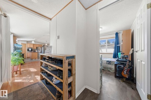 Open concept living area with light wood flooring and a view into the kitchen featuring wood cabinetry and stainless steel appliances - 66 Evergreen Park, Edmonton, AB - Indoor Photo Showing Other Room