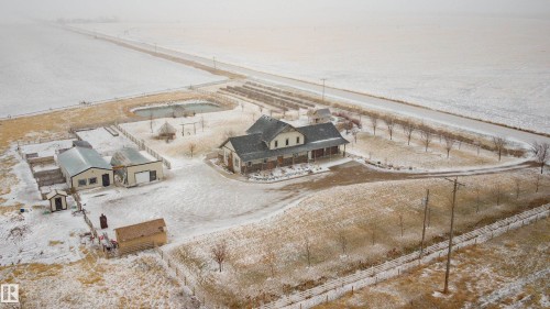 Expansive property featuring a main residence with a covered porch, several outbuildings, a pond, and a fenced perimeter - 114039 Range Road 221, Rural Lethbridge County, AB - Outdoor