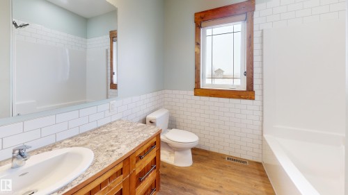 Bathroom featuring a wood vanity with a white sink, a mirror, and white subway tile wainscoting - 114039 Range Road 221, Rural Lethbridge County, AB - Indoor Photo Showing Bathroom