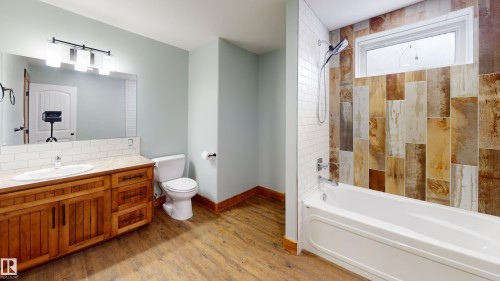 The bathroom features a vanity with a wood cabinet, a white sink, and a large mirror - 114039 Range Road 221, Rural Lethbridge County, AB - Indoor Photo Showing Bathroom