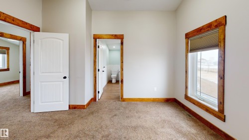 This room features warm neutral wall colors, a large window with wooden trim, and carpeted flooring - 114039 Range Road 221, Rural Lethbridge County, AB - Indoor Photo Showing Other Room