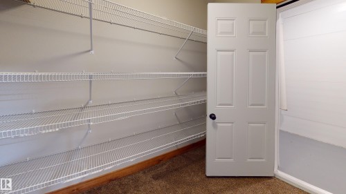 This space features white wire shelving providing ample storage, a paneled door, and carpeted flooring - 114039 Range Road 221, Rural Lethbridge County, AB - Indoor With Storage
