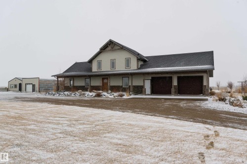 The property features a residence with a light-colored exterior, a dark roof, and a two-car garage - 114039 Range Road 221, Rural Lethbridge County, AB - Outdoor