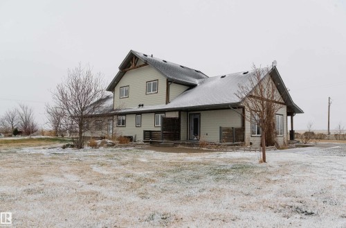 The property features a two-story design with light-colored siding and a dark shingled roof, partially covered in snow - 114039 Range Road 221, Rural Lethbridge County, AB - Outdoor