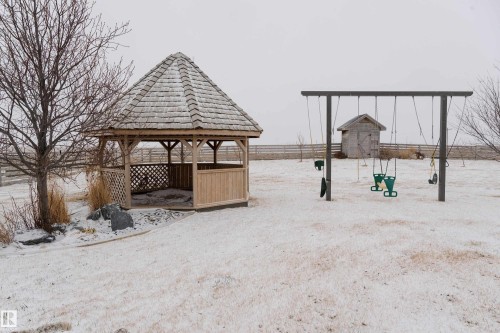 The property features an outdoor gazebo with a shingle roof and lattice detailing, alongside a swing set - 114039 Range Road 221, Rural Lethbridge County, AB - Outdoor
