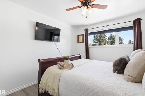 This room features a ceiling fan with integrated lighting, a window with a view of trees, and hard surface flooring - 12904 95 Street, Edmonton, AB - Indoor Photo Showing Bedroom
