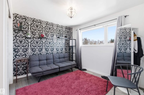 This room features a distinct accent wall with black and white patterned wallpaper, complemented by light grey flooring and a bright window - 12904 95 Street, Edmonton, AB - Indoor