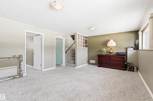 Spacious room featuring light-colored carpet, a window, and a staircase - 12904 95 Street, Edmonton, AB - Indoor Photo Showing Bedroom