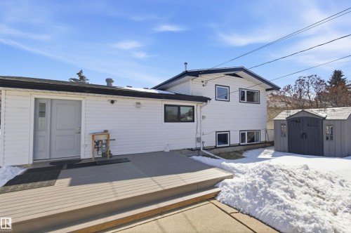 Rear exterior view of the property, featuring white siding, a multi-level deck, and a detached shed - 12904 95 Street, Edmonton, AB - Outdoor With Exterior