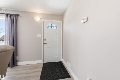The entry features a front door with a decorative glass insert, light gray walls, and light-colored flooring - 12904 95 Street, Edmonton, AB - Indoor Photo Showing Other Room