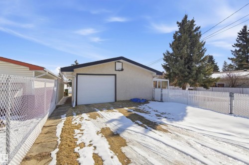 The property features a detached garage with a white overhead door and a paved driveway - 12904 95 Street, Edmonton, AB - Outdoor With Exterior