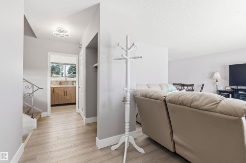 The property features light-colored flooring throughout the main entry area and into the adjacent room, which includes wood-toned cabinetry and a window - 12904 95 Street, Edmonton, AB - Indoor