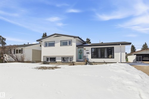 The property features white siding with black trim, a black shingle roof, and visible foundation stonework - 12904 95 Street, Edmonton, AB - Outdoor With Facade