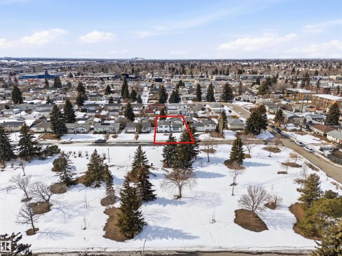 Aerial view of the property and surrounding neighborhood, featuring a residential street and a park area with snow-covered ground and evergreen trees - 12904 95 Street, Edmonton, AB - Outdoor With View