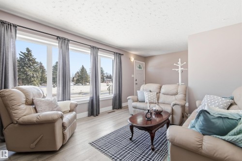 The living area features light-toned walls, light-colored flooring, and large windows with privacy drapes - 12904 95 Street, Edmonton, AB - Indoor Photo Showing Living Room