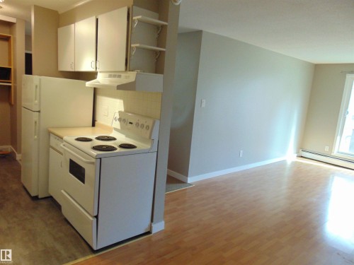 Kitchen area with white cabinetry and appliances, including an electric range with range hood and refrigerator - 8 10616 123 Street, Edmonton, AB - Indoor Photo Showing Kitchen