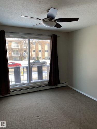 Sliding glass door to balcony, ceiling fan with integrated lighting, wall-to-wall carpeting, baseboard heating, and neutral wall tones - 8 10616 123 Street, Edmonton, AB - Indoor Photo Showing Other Room