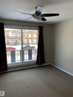 Sliding glass door to balcony, ceiling fan with integrated lighting, wall-to-wall carpeting, baseboard heating, and neutral wall tones - 