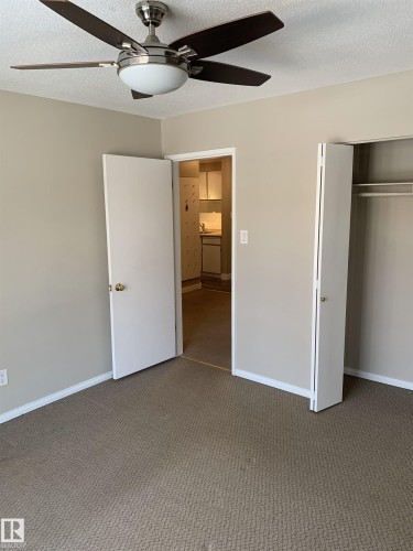 Carpeted room with a ceiling fan featuring a brushed nickel finish and wood-finish blades - 8 10616 123 Street, Edmonton, AB - Indoor Photo Showing Other Room