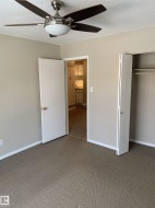 Carpeted room with a ceiling fan featuring a brushed nickel finish and wood-finish blades - 