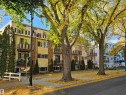The property features a multi-story building with balconies, a tan stucco exterior, and brick accents - 8 10616 123 Street, Edmonton, AB  - Outdoor With Facade 