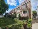 The property features a brick and stucco exterior with balconies, surrounded by a landscaped lawn with mature trees and shrubbery - 8 10616 123 Street, Edmonton, AB  - Outdoor 
