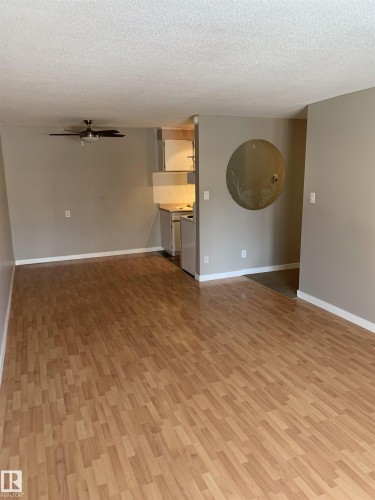 Wood-finish flooring throughout the main living area - 8 10616 123 Street, Edmonton, AB - Indoor Photo Showing Other Room