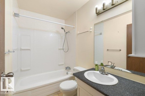 The bathroom features a bathtub with a shower, a vanity with an integrated sink, and a large mirror - 17313 60 Avenue, Edmonton, AB - Indoor Photo Showing Bathroom