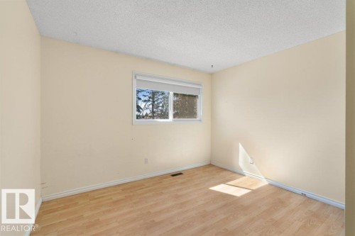 This room features a window with a white frame and blinds, light-colored walls, and wood-style flooring - 17313 60 Avenue, Edmonton, AB - Indoor Photo Showing Other Room