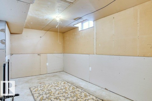 The property features an unfinished room with a concrete floor, partial drywall on the walls, and a window providing natural light - 17313 60 Avenue, Edmonton, AB - Indoor