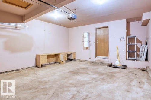 The property features a garage with a concrete floor, painted walls, and a visible garage door opener mechanism - 17313 60 Avenue, Edmonton, AB - Indoor