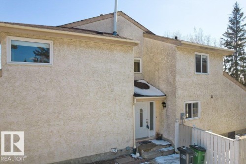The property features a stucco exterior, a white front door with decorative glass inserts, and multiple windows with white frames - 17313 60 Avenue, Edmonton, AB - Outdoor With Exterior