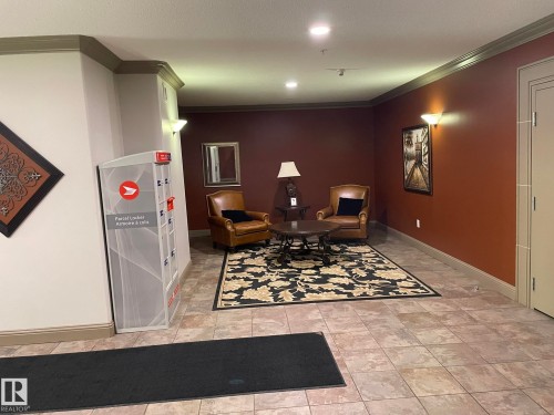 The property features a welcoming common area with tiled flooring, a decorative area rug, and two brown leather armchairs - Edmonton, AB - Indoor Photo Showing Other Room