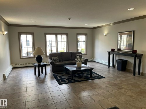 The room features tiled flooring, multiple windows providing natural light, and crown molding - Edmonton, AB - Indoor Photo Showing Living Room