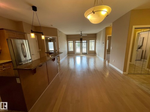 The open concept living area features hardwood flooring, a ceiling fan, and French doors leading to an outdoor space - Edmonton, AB - Indoor