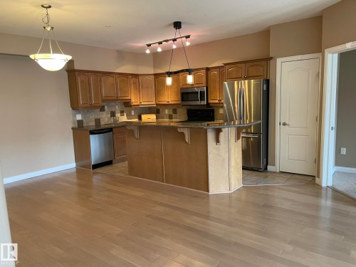 The kitchen features wood cabinetry, stainless steel appliances, and a tiled backsplash - Edmonton, AB - Indoor Photo Showing Kitchen With Stainless Steel Kitchen